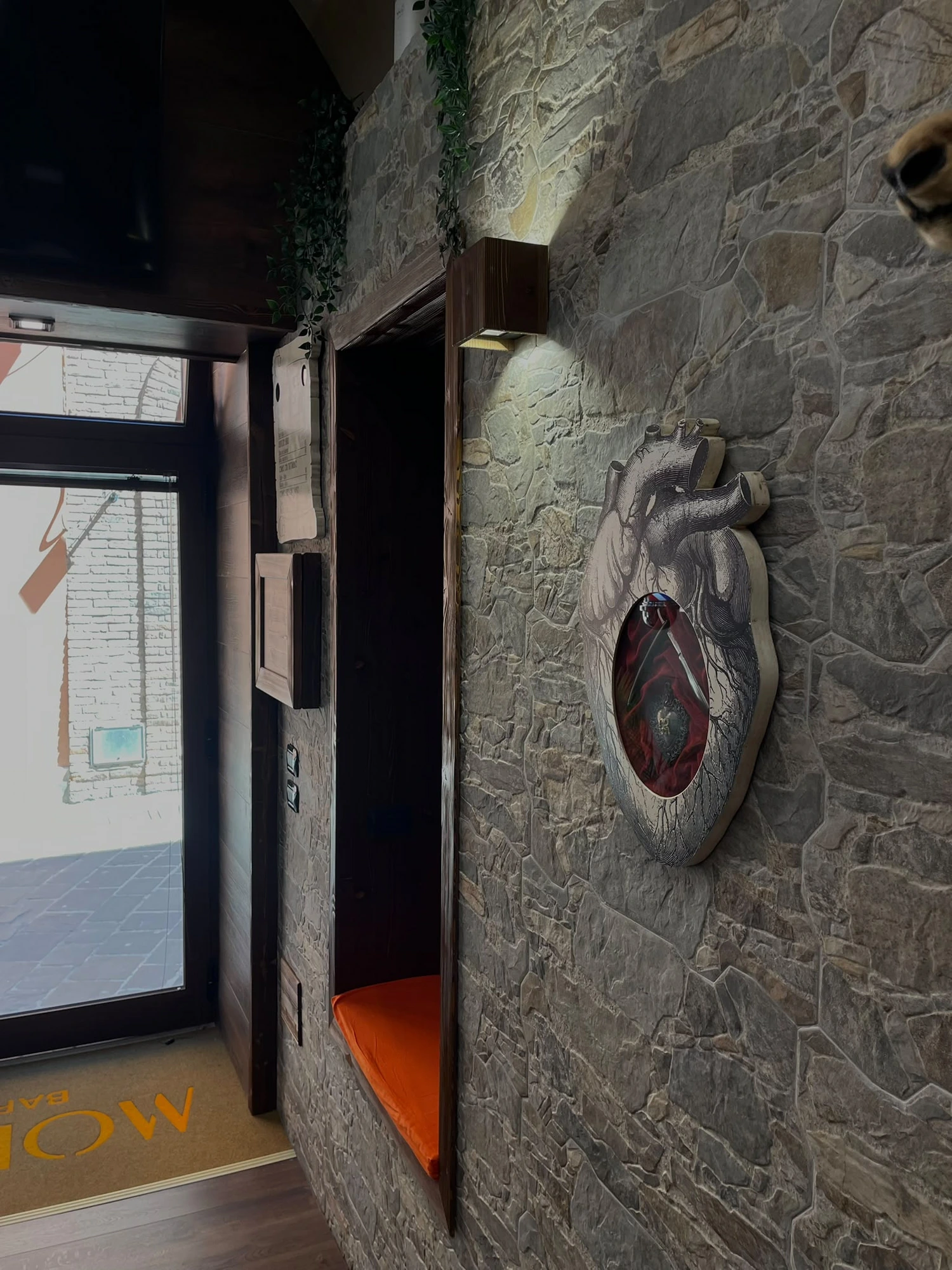 Ingresso di Modico Barberia con muro in pietra e nicchia arancione