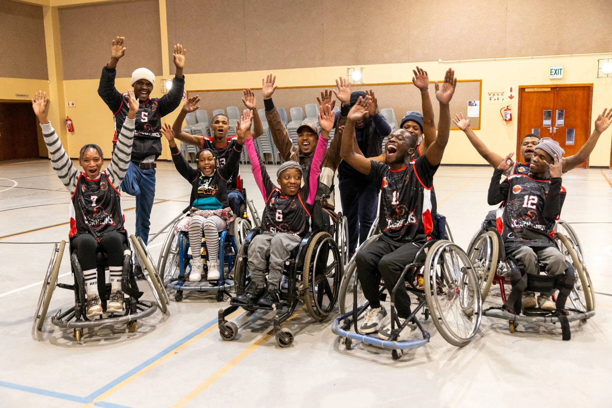 Langa Scorpions team celebrating in their red-and-black kit at the community sports hall