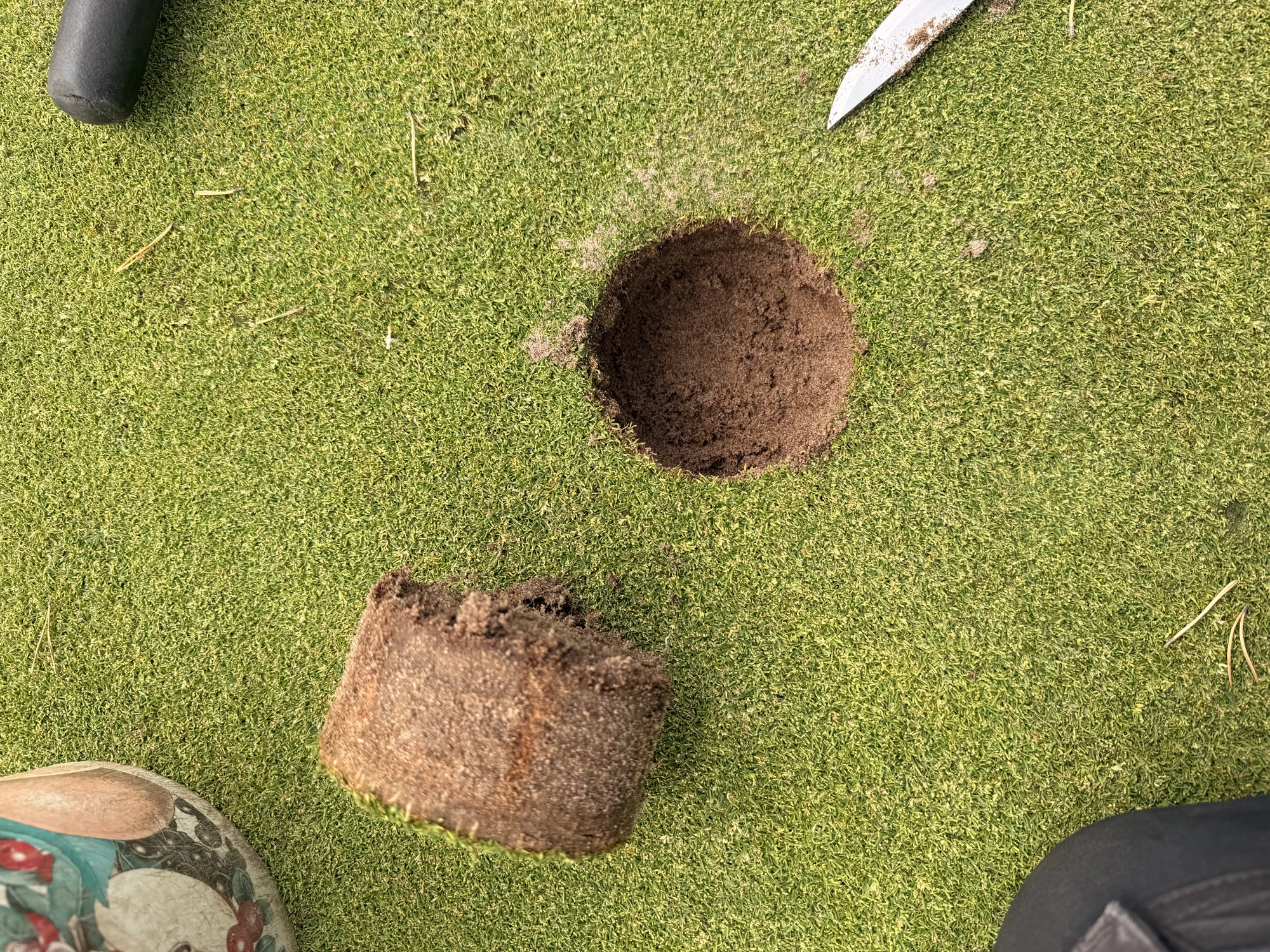 Greenkeeper changing a hole on a putting green