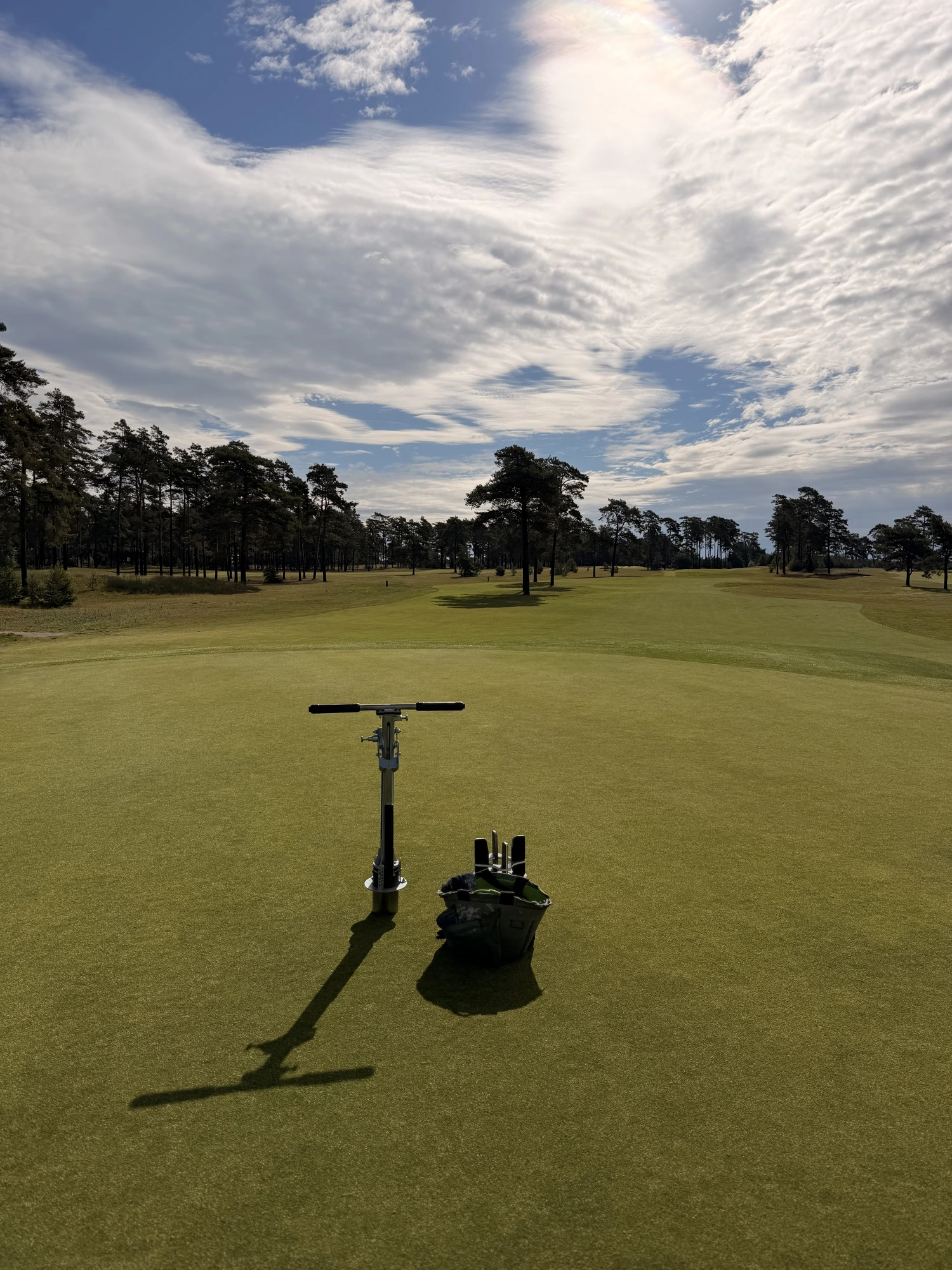 Immaculate green with maintenance tools under a bright sky