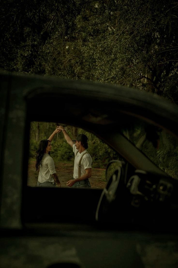 A couple dancing framed through a dark car window, cinematic film photograph