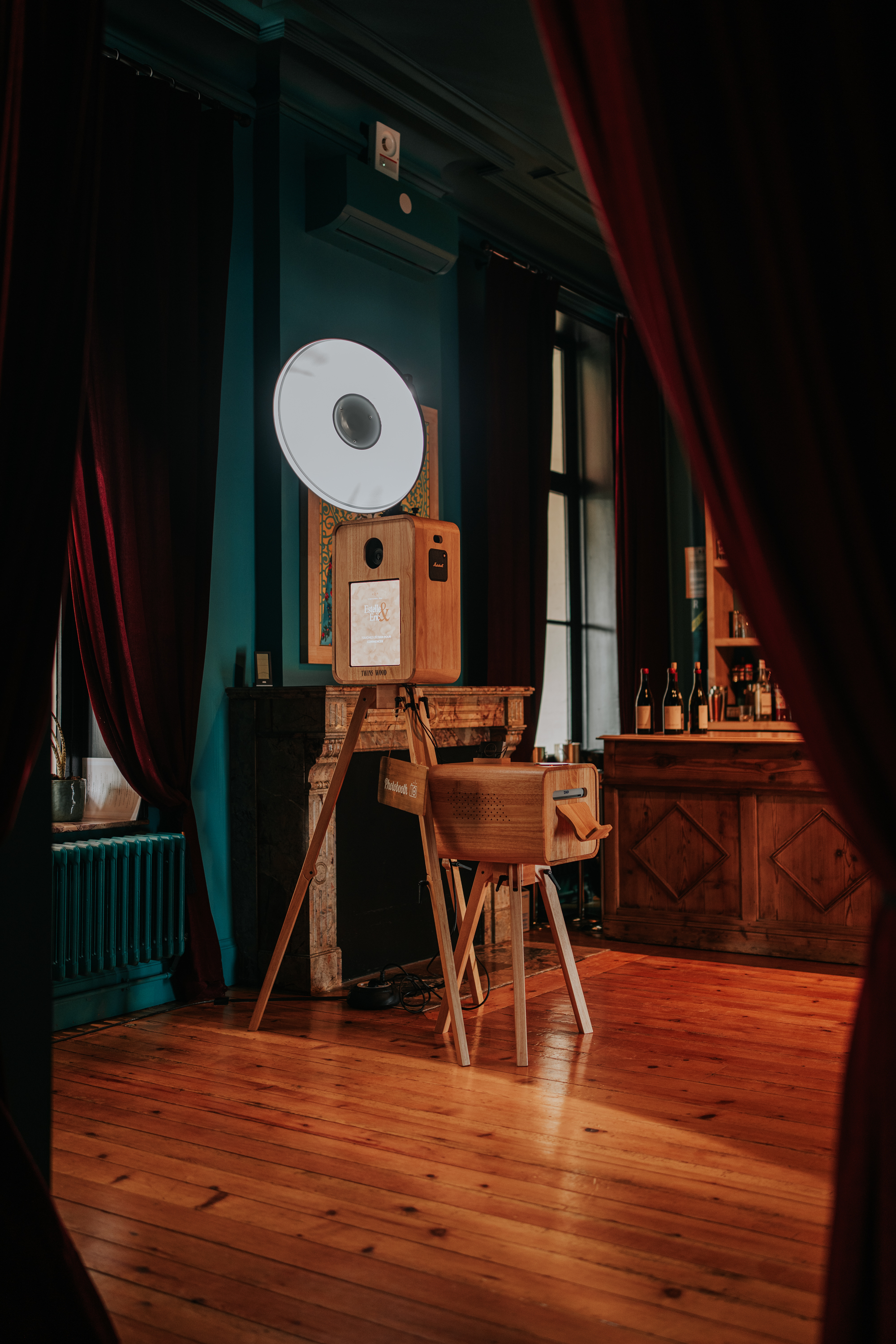 Le photobooth Twins Wood installé dans le salon élégant du Château de Bry, avec ses murs bleu canard et rideaux de velours bordeaux